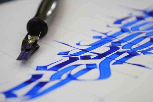 Calligraphy nib, ink bottle, and lettering practice on kraft paper